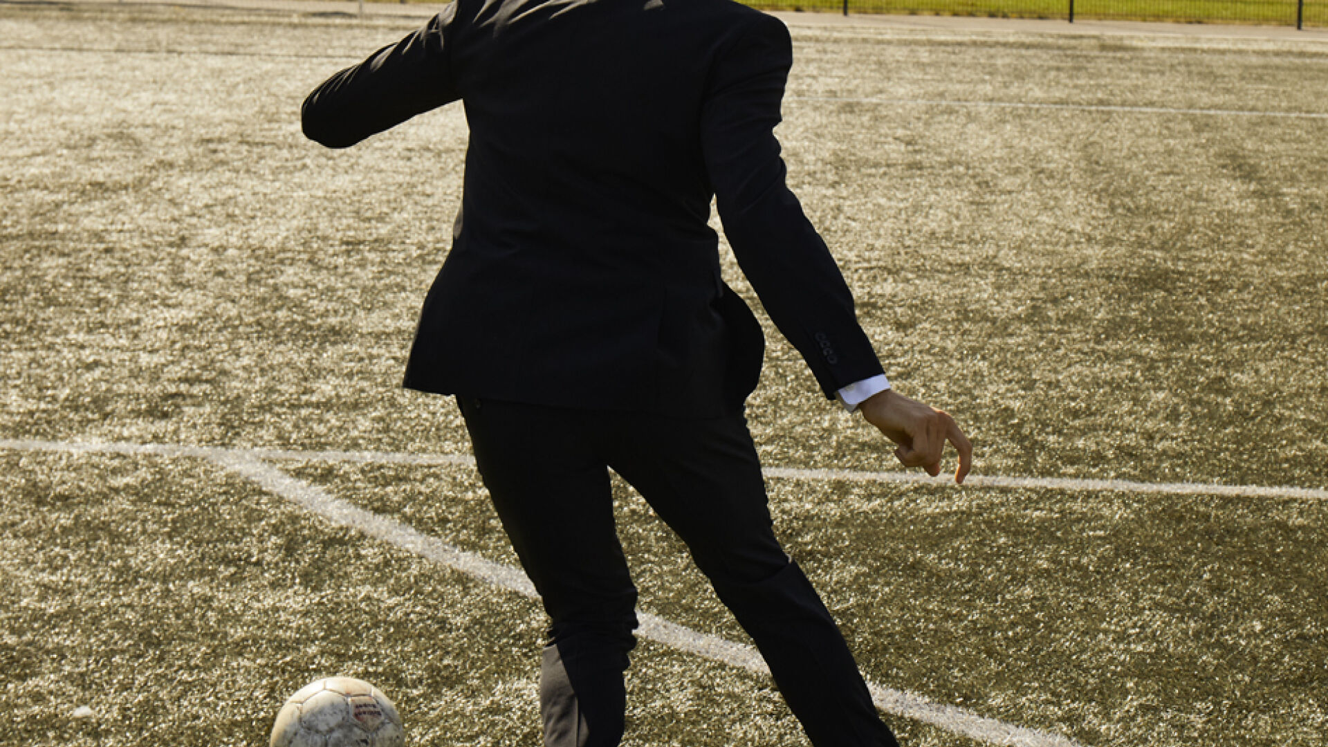 Fußballspieler im schwarzen Lindbergh-Anzug, der einen Fußball kickt